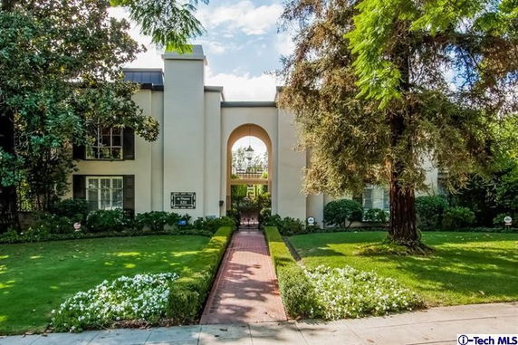Front view of a two-story building with arches and landscaped garden.