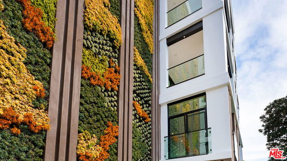 Side view of a modern multi-story building with a living wall covered in colorful plants.