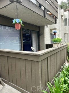 Front view of a two-story building with a balcony and potted plants.