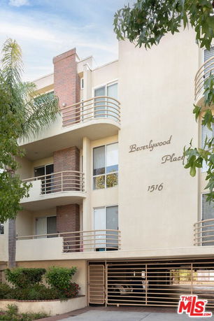 Front view of a multi-story residential building with balconies and brick facades.