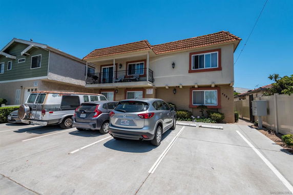 Front view of a two-story building with visible parking spaces for vehicles.