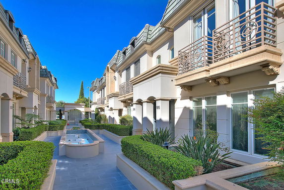 Front view of a row of modern townhouses with balconies and a central courtyard.