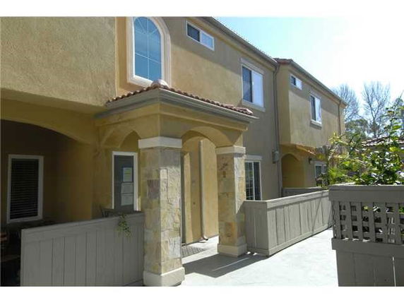 Front view of a two-story house with an archway entrance and a balcony.