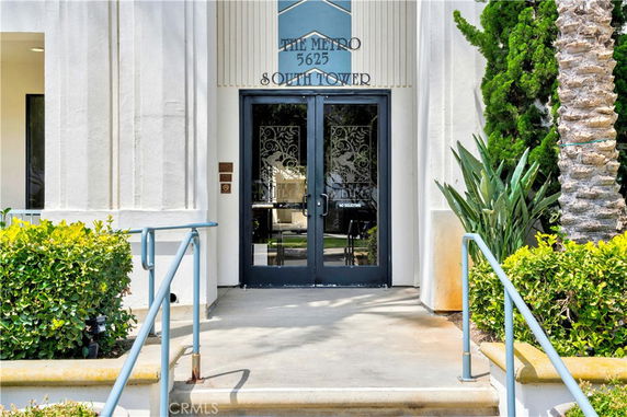 Front entrance of a building labeled The Metro South Tower with double glass doors.