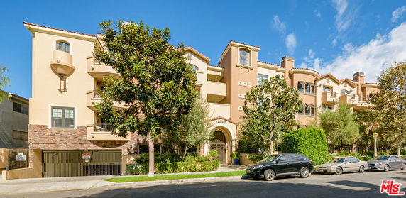 Front view of a multi-story residential building with balconies and an arched entryway.