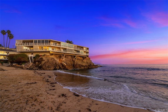 Front view of a multi-story house situated on a rocky coastline.