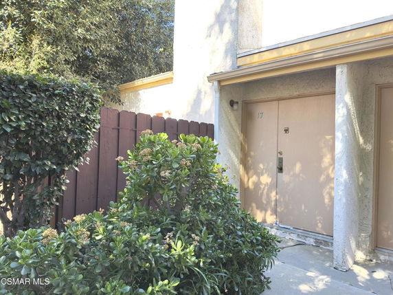 Front view of a house entrance with a wooden fence and plants.