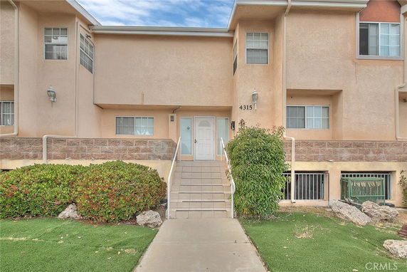 Front view of a two-story townhouse with a staircase leading to the entrance.