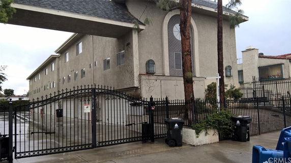 Front view of a multi-story residential building with a gated entrance.