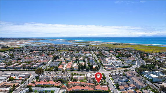 Panoramic aerial view of a coastal residential area with numerous houses and a beach in the background.