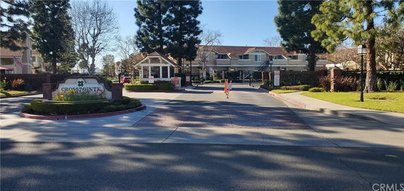Front view of a residential complex entrance with a gated entrance and security post.