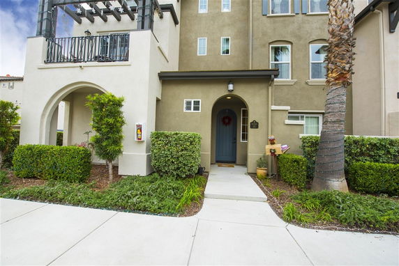 Front view of a multi-story house with an arched entryway and balcony.