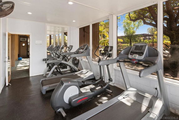 Indoor gym area with multiple treadmills and large windows.