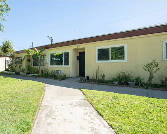 Front view of a single-story house with beige exterior and a small walkway leading to the entrance.