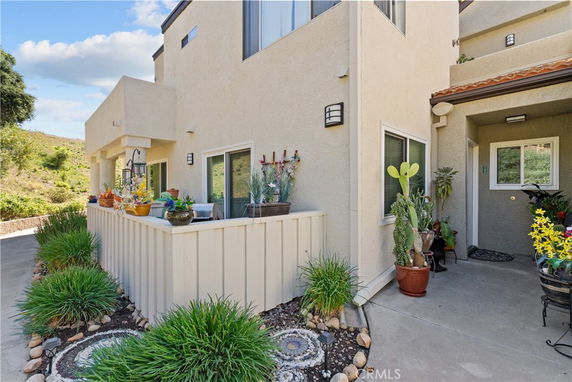 Front view of a modern multi-story house with a small patio and decorative plants.