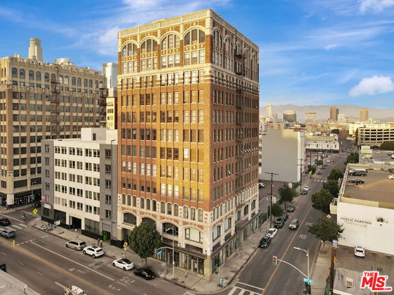 Front view of a tall, multi-story brick building at a street corner.