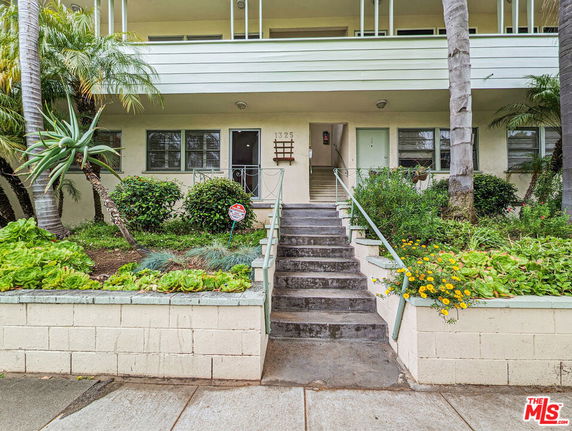 Front view of a residential building with stairs leading to the entrance.