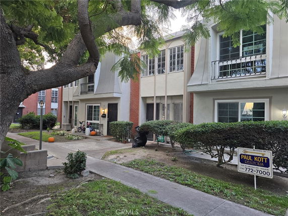 Front view of a multi-story townhouse with balconies and a walkway.