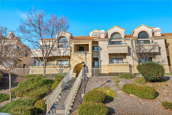 Front view of a multi-story residential building with a staircase leading up to the entrance.