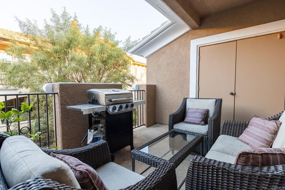 Outdoor seating area with wicker furniture and a grill on a balcony.