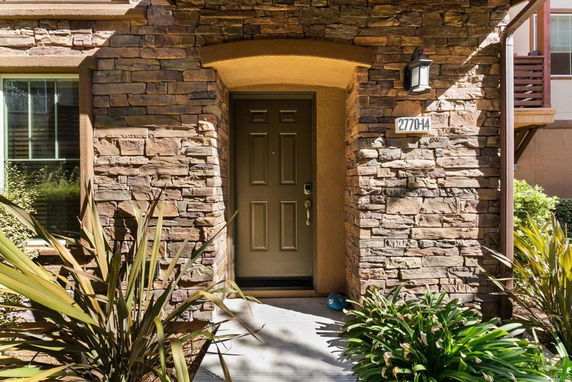 Front view of a house with stone facade and a brown door.