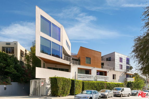 Front view of a modern multi-story building with large windows and varied exterior materials.