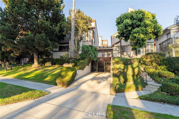 Front view of a multi-story residential building with trees and a driveway leading to an underground parking area.