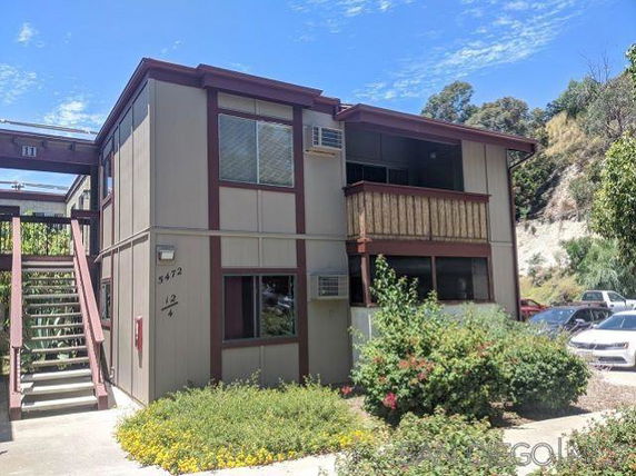Front view of a two-story residential building with a balcony and exterior stairway.