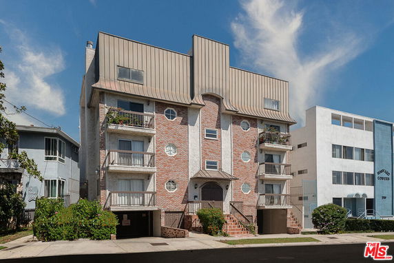 Front view of a multi-story building with a brick facade and balconies.