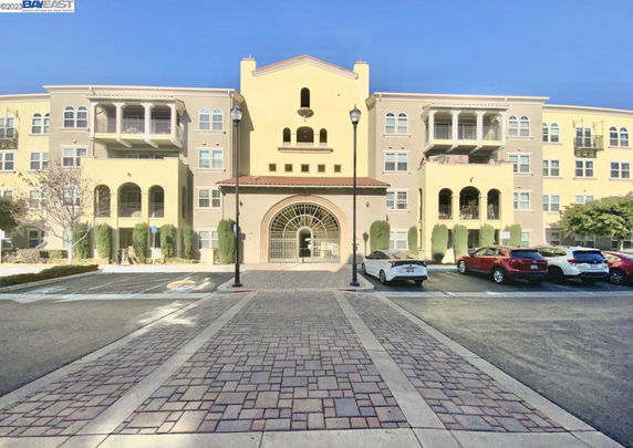 Front view of a multi-story residential building with balconies and an arched entrance.