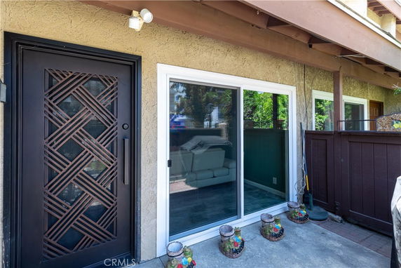 Front view of a house with a decorative metal door and sliding glass door.