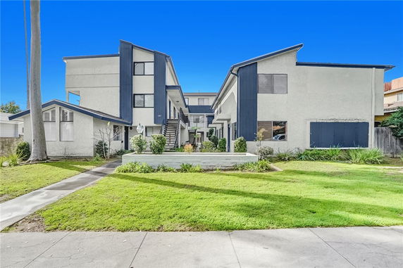 Front view of a modern multi-story building with blue accents and landscaped entrance.