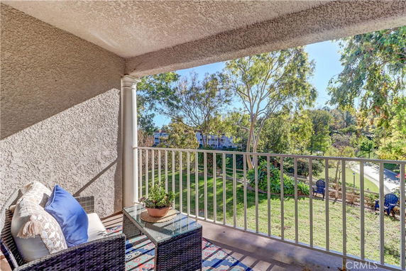 View from a balcony overlooking a garden with trees and lounge chairs.