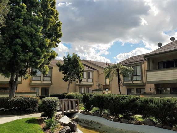 Front view of a multi-story residential building with balconies and trees.