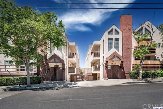 Front view of a multi-story residential building with balconies and triangular roof accents.