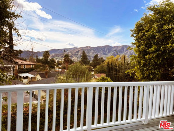 Panoramic view from a balcony overlooking houses and distant mountains.