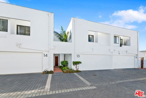Front view of a modern two-story townhouse with white exterior and garage.