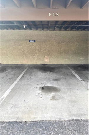 Outdoor covered parking space marked F13 with parking lines and a sign indicating not to back in.
