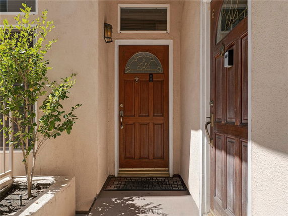 Front view of a building entrance with a wooden door and a decorative window panel.