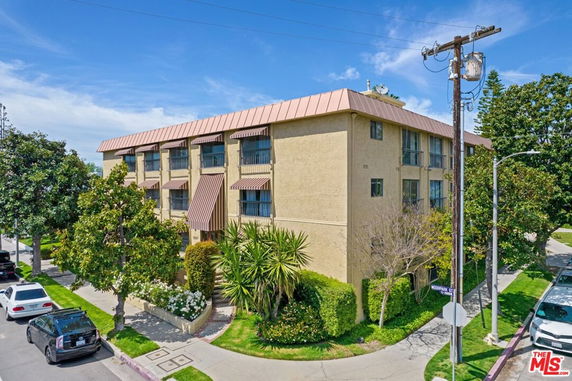 Front view of a three-story building with a slanted roof and multiple windows.