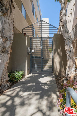 Entrance gate of a multi-story building with metal gate and concrete path.
