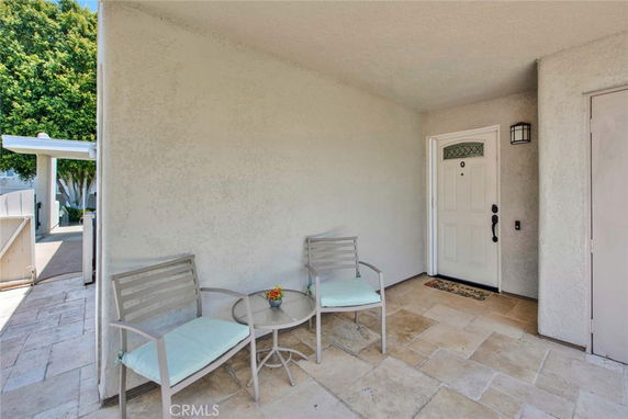 Front entrance of a house with a small seating area and a white front door.