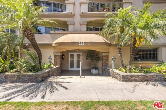 Front view of a multi-story building with balconies and a front entrance canopy.