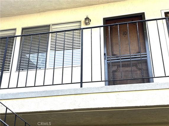 Front view of a building with a door and windows on an upper floor.