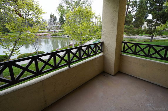 View from a balcony overlooking a pond and trees.