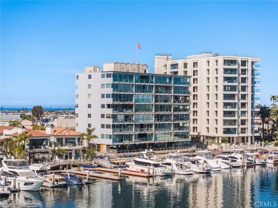 Front view of a multi-story apartment building with balconies near a marina.
