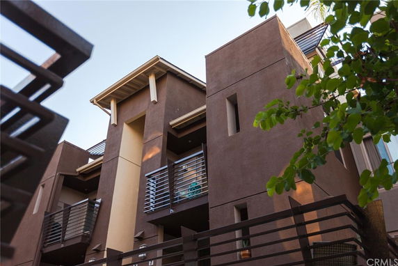 Front view of a modern multi-story building with brown exterior and balconies.