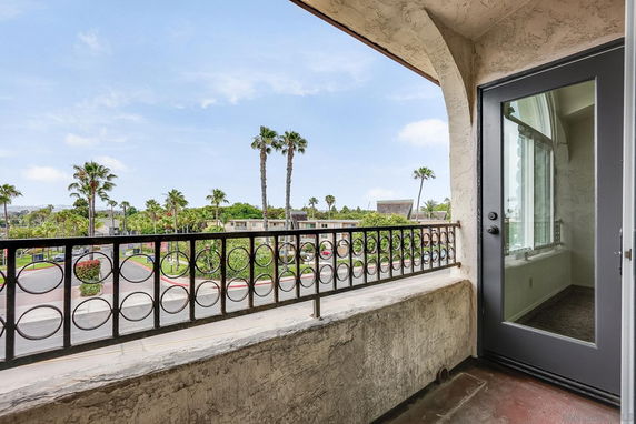View of surrounding area from a balcony with wrought iron railing and glass door.