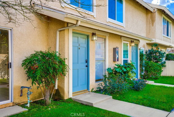 Front view of a house with two blue doors and beige walls.