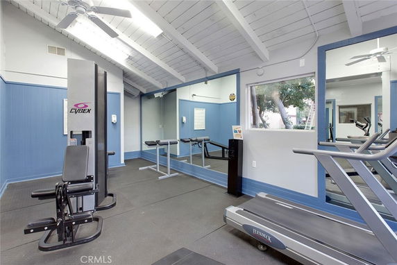 Indoor gym area with exercise equipment and mirrors on the walls.